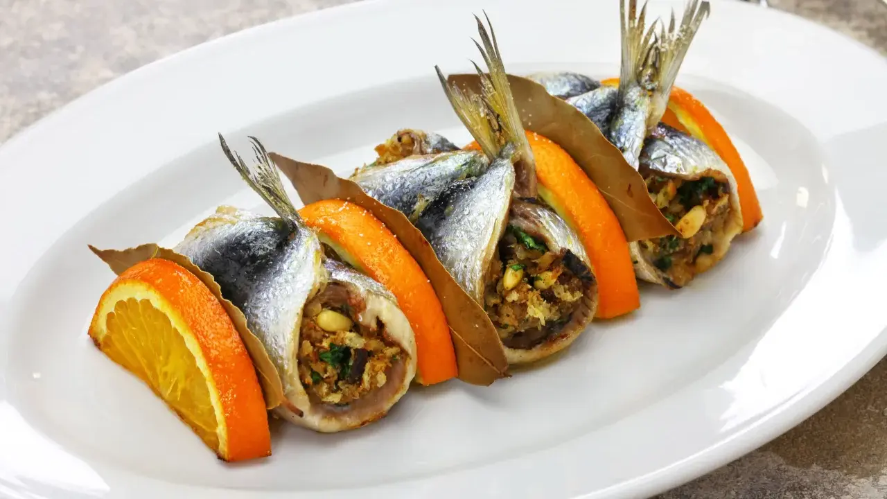 Sardine ripiene, un'esplosione di sapori mediterranei, tra le specialità siciliane salate. Arancia, alloro e un ripieno gustoso.