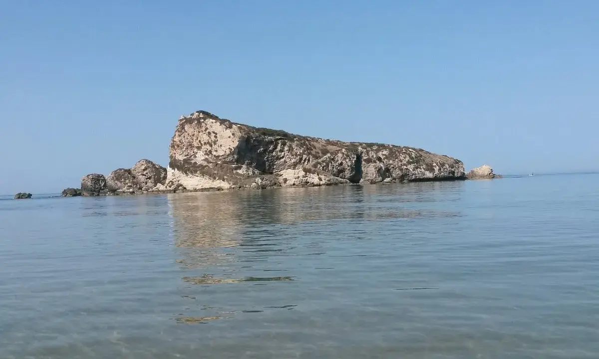 La Rocca San Nicola a Licata, imponente roccia calcarea che emerge dal mare cristallino, sotto un cielo azzurro.