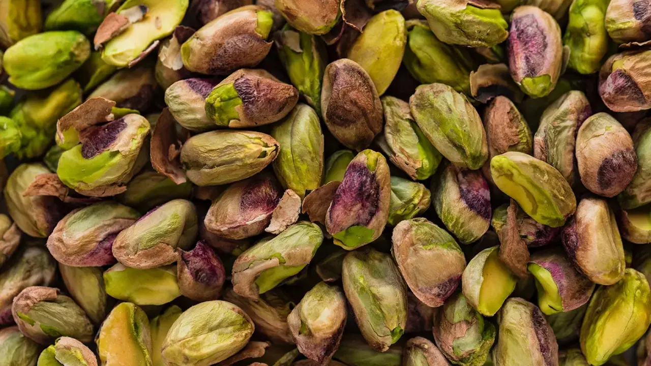 Un mucchio di pistacchi, alcuni con il guscio screpolato che rivela il loro interno verde brillante, ricordano il sapore del pistacchio in siciliano.