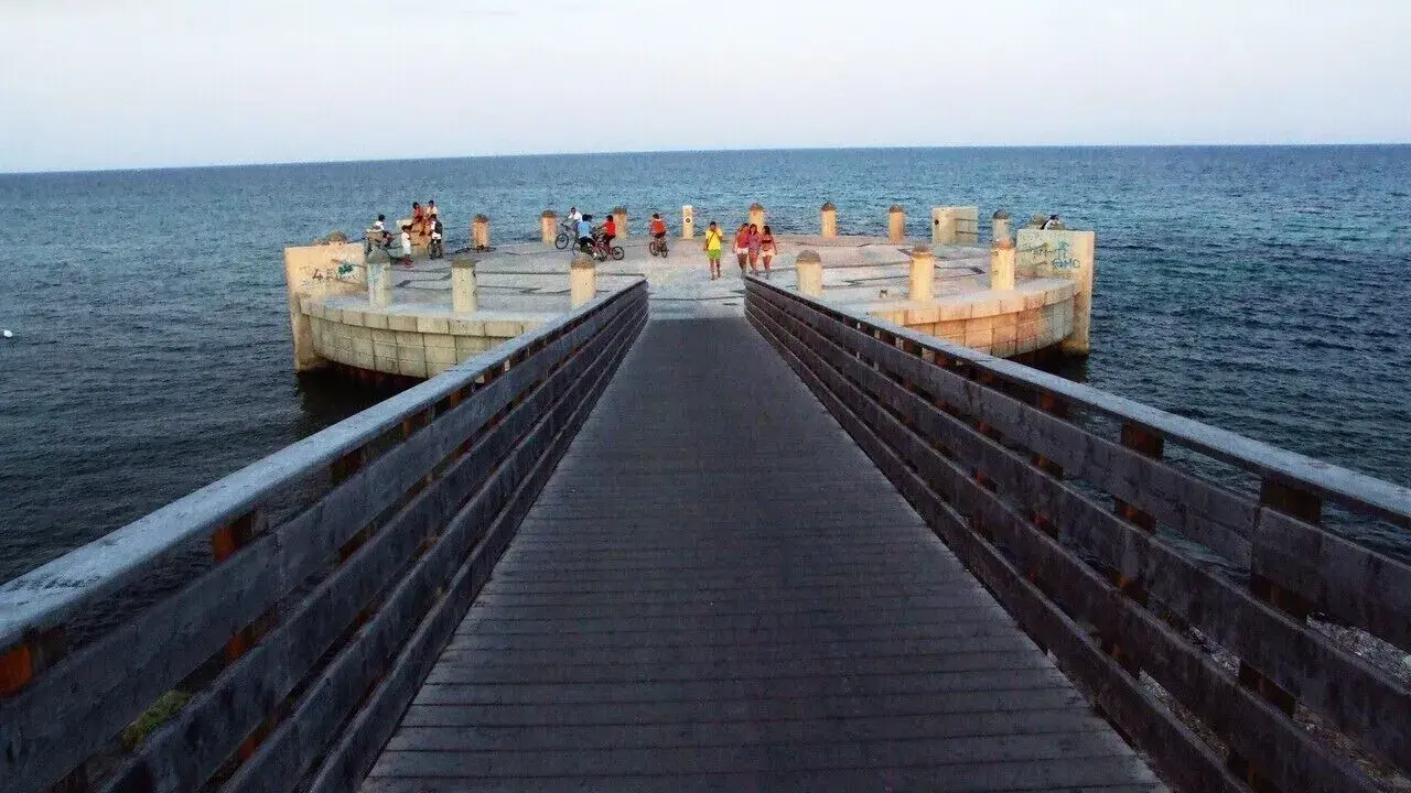 Passeggiata sul lungomare di Avola di sera, con persone che si godono la vista dal molo circolare.