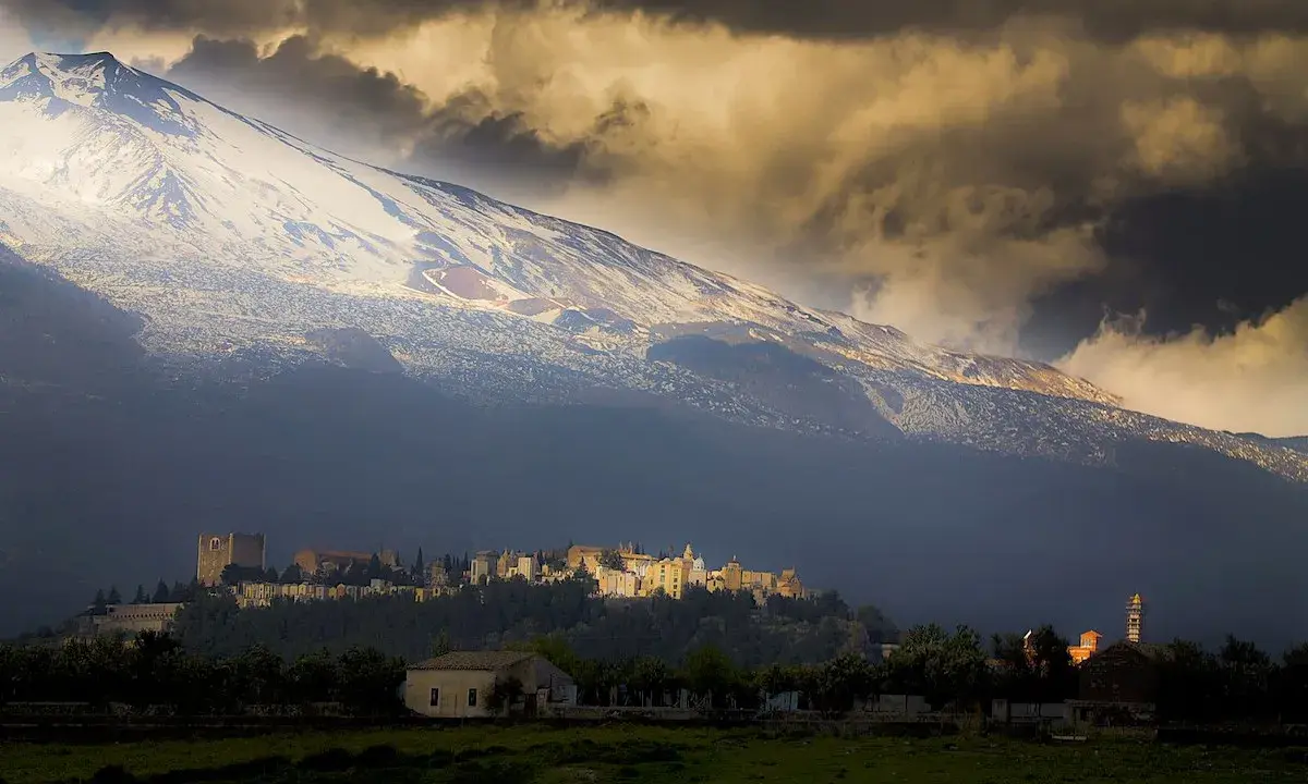 Villaggio ai piedi dell'Etna, vulcano imponente. L'etimologia del nome "Etna" evoca un fuoco eterno, come quello che arde sotto la neve.
