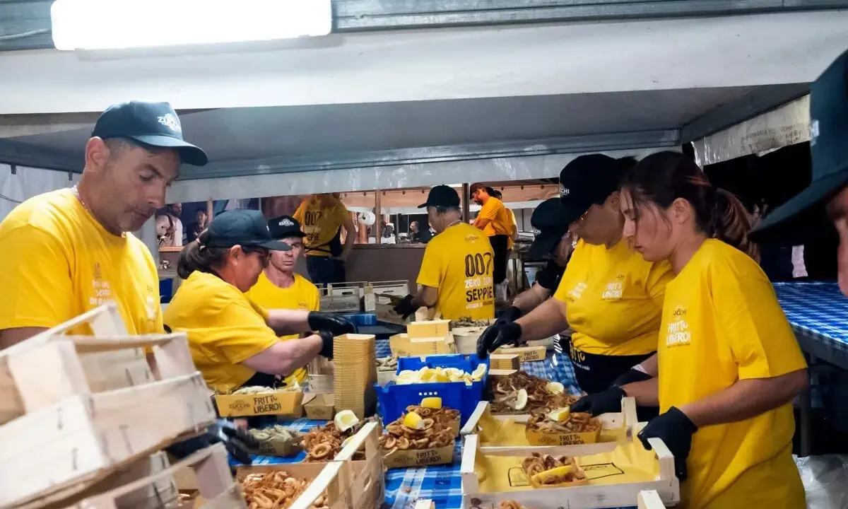 Persone in maglietta gialla servono fritto misto in un evento serale. Un'ottima idea per cosa fare a Salerno la sera, gustando specialità locali.