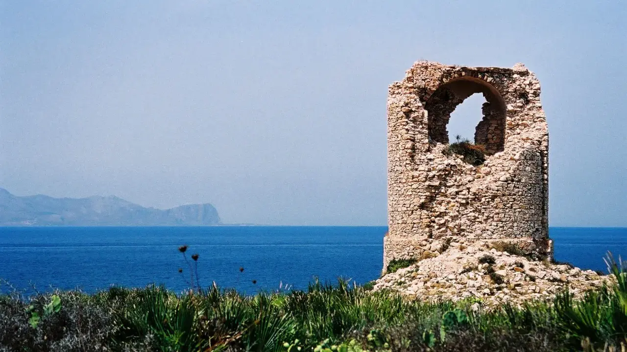 Torre saracena in rovina, un luogo suggestivo da scoprire a Terrasini, con il mare blu e le montagne sullo sfondo.