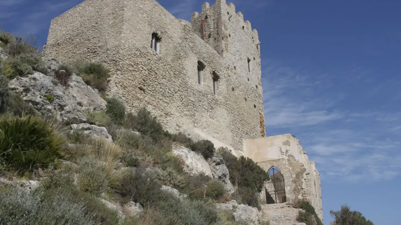 Antica fortezza, la Madonna del Castello di Palma di Montechiaro, si erge su un colle roccioso sotto un cielo azzurro.