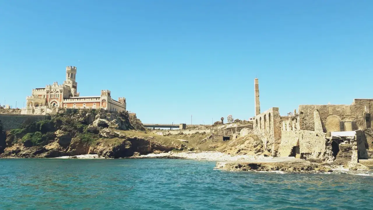 Antica tonnara di Portopalo con il castello sulla scogliera e le rovine di un'antica struttura industriale.