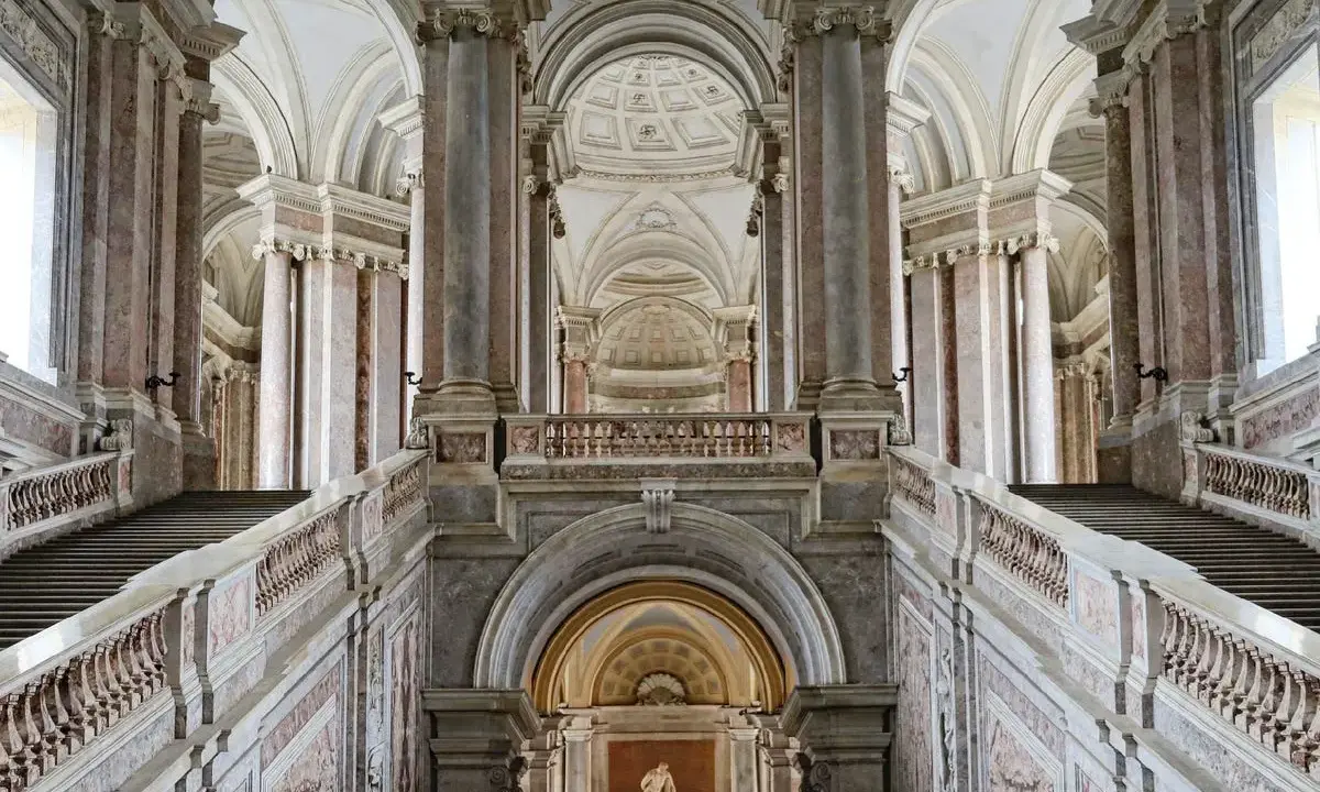 Magnifici interni della Reggia di Caserta: scalinate imponenti, marmi pregiati e volte maestose creano un'atmosfera regale.