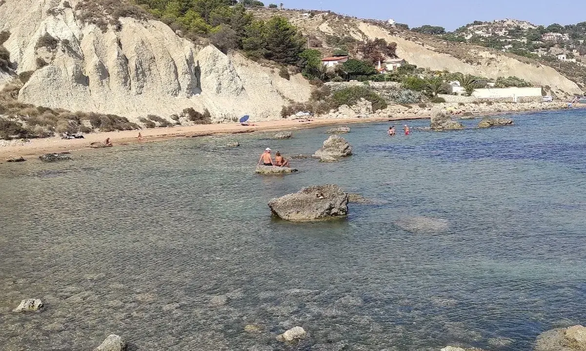 La spiaggia di Marianello a Licata, con scogliere bianche, acque cristalline e bagnanti che si godono il sole.