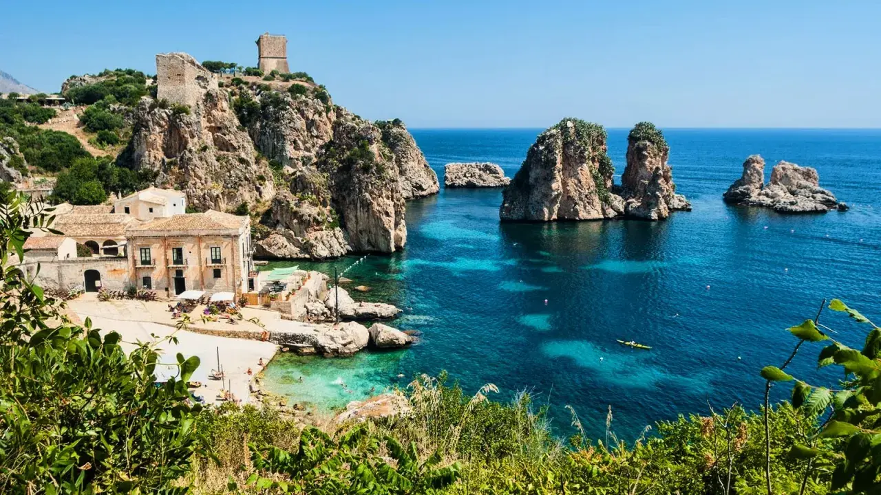 Baia con faraglioni e torri antiche, ideale per scoprire come arrivare a Scopello e godersi il mare cristallino.