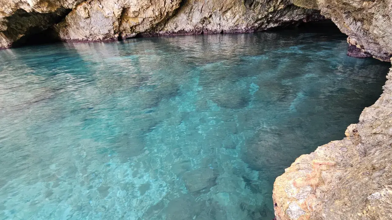 Acque cristalline nella baia di San Cataldo, con rocce calcaree che creano un'atmosfera suggestiva.