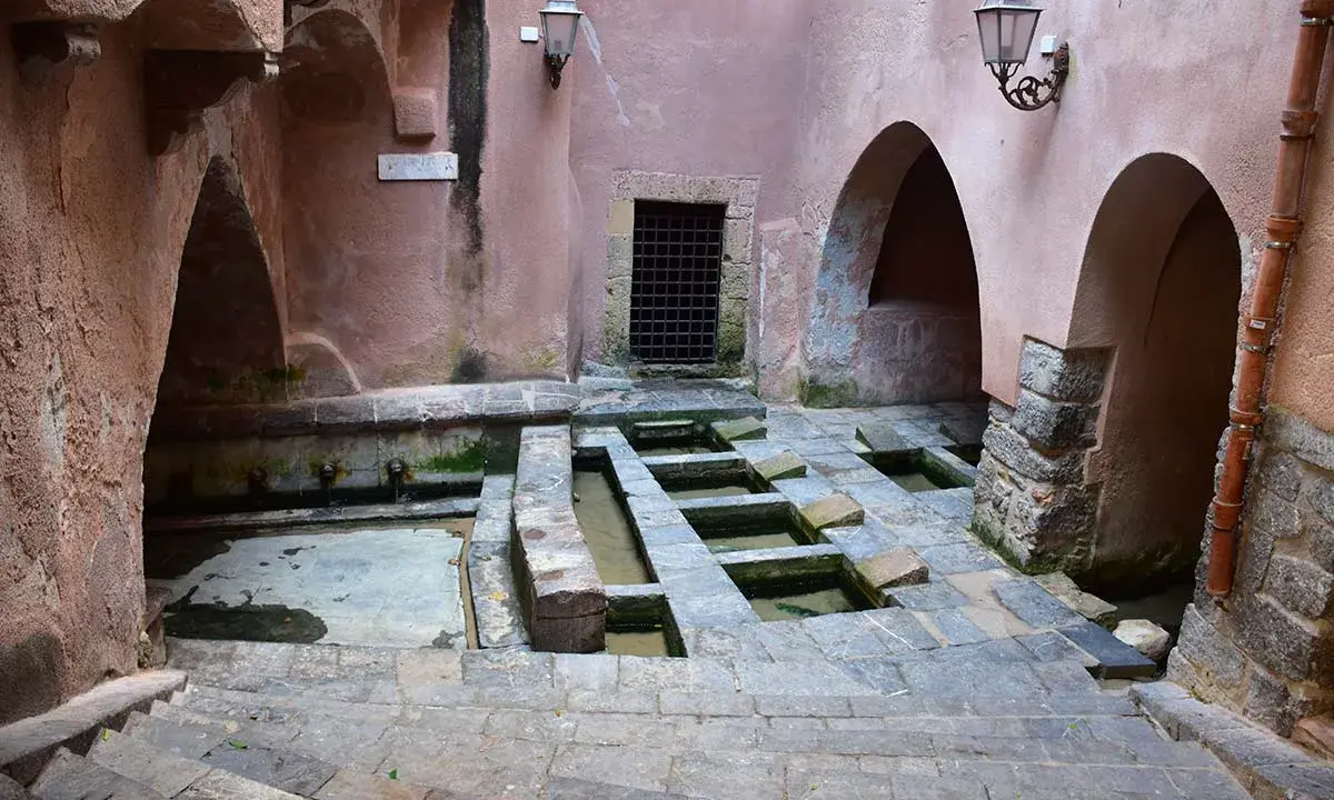 Antico lavatoio a Cefalù, con vasche in pietra e archi in rosa antico.