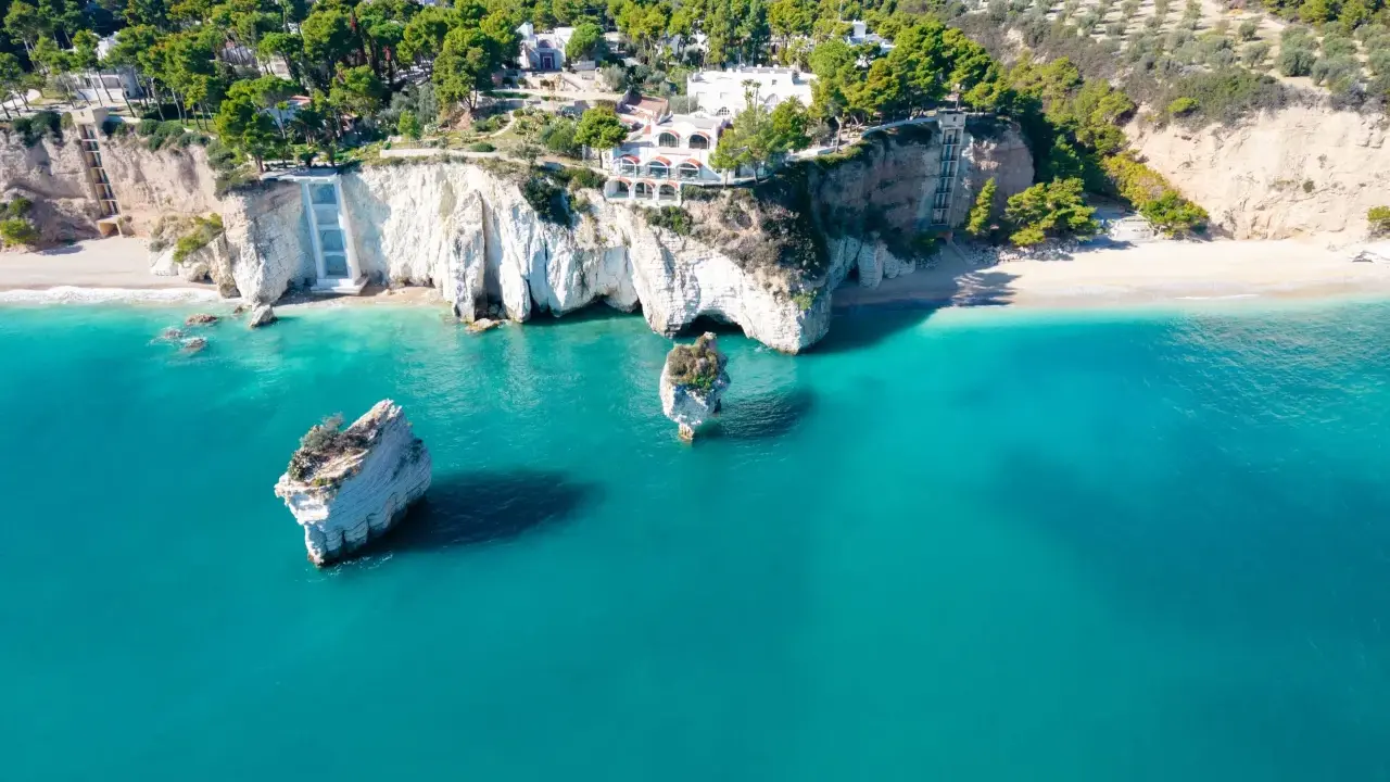 Scogliere bianche a picco sul mare turchese, con rocce isolate e vegetazione lussureggiante. Un vero angolo di paradiso tra le spiagge più belle della Puglia.