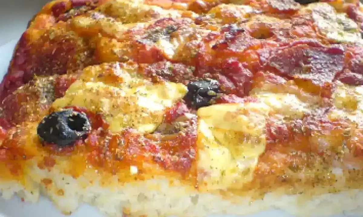 Una fetta di pizza muddiata, con pomodoro, formaggio filante, salame e olive nere, condita con erbe aromatiche.