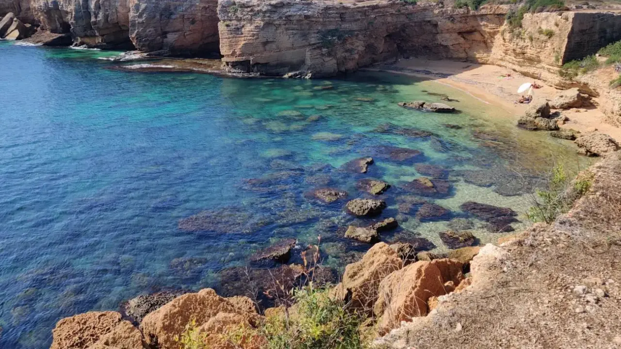 Acque cristalline e scogliere dorate incorniciano la spiaggia di Massolivieri, un angolo di paradiso con rocce affioranti.