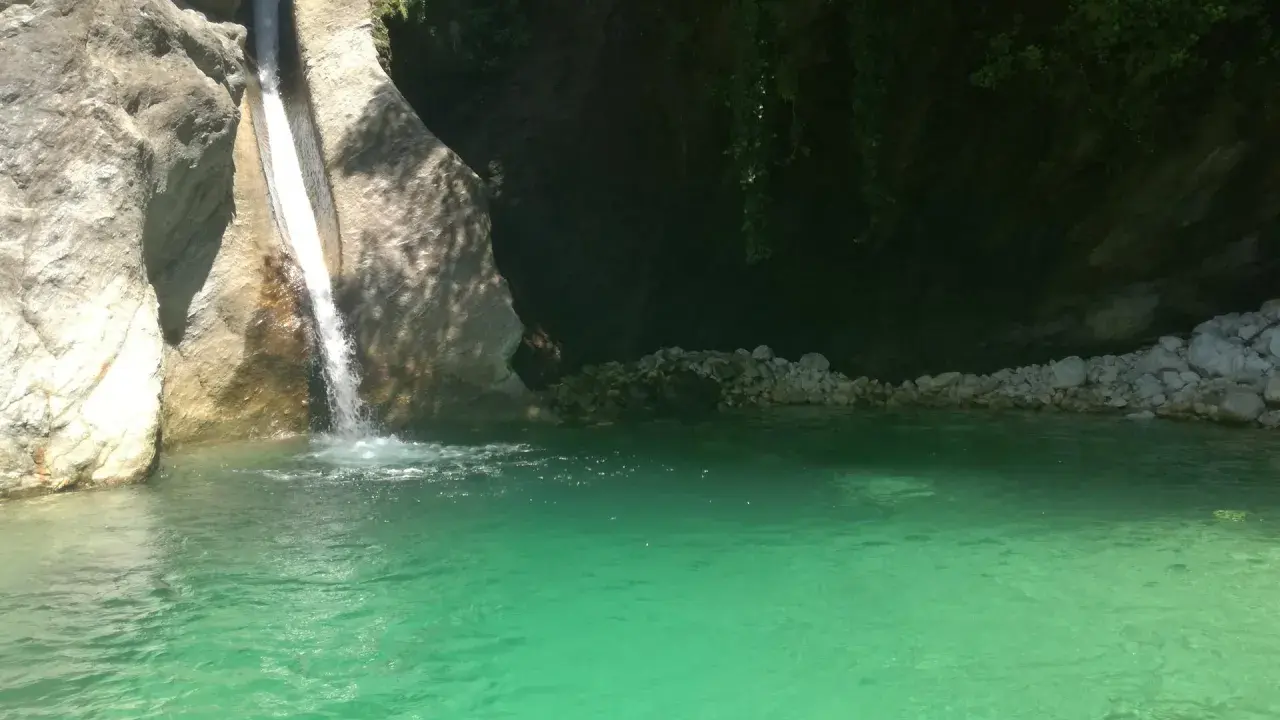 Cascata che si getta nella **pozza della Madonna**, un'oasi di acqua cristallina tra rocce e vegetazione rigogliosa.