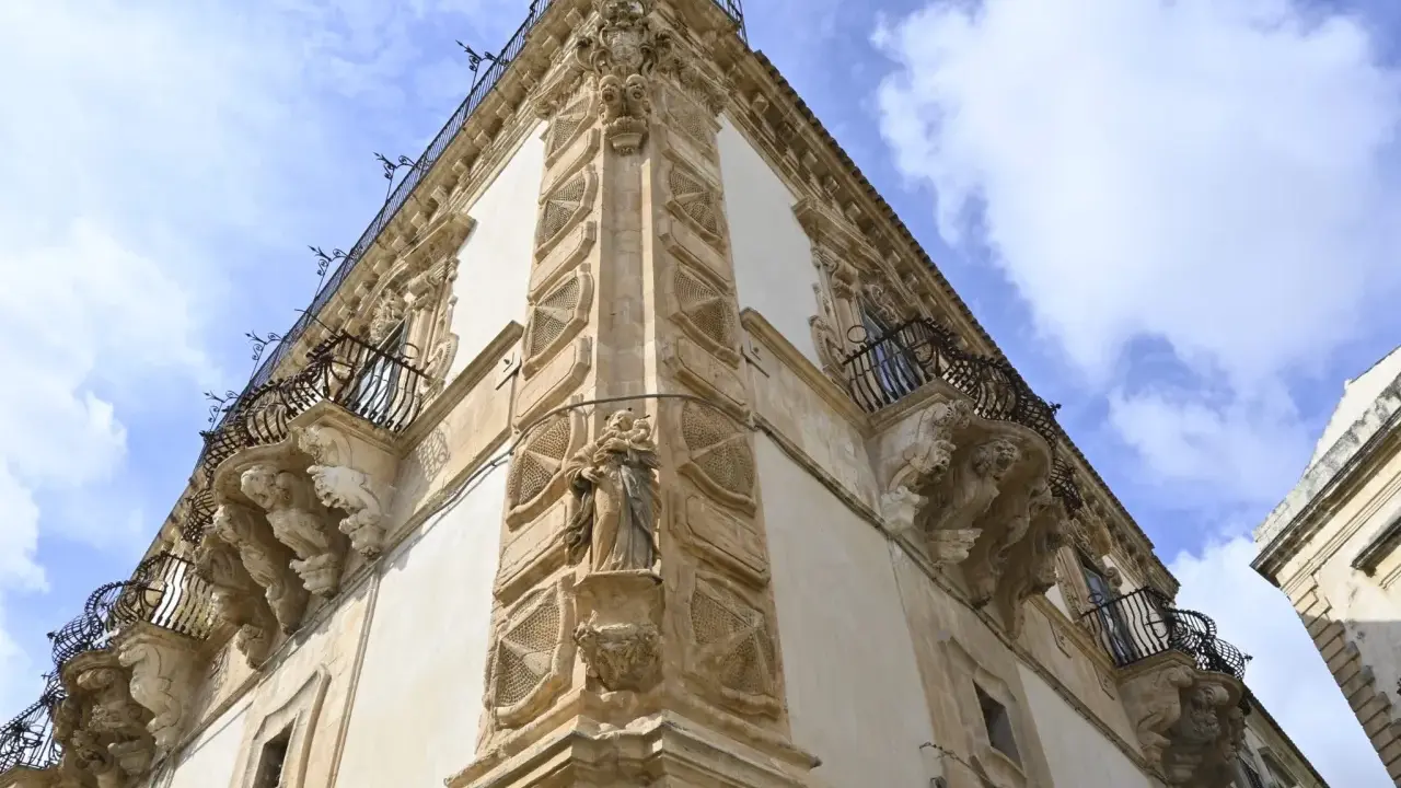 Angolo del palazzo Beneventano a Scicli, con balconi in ferro battuto e sculture barocche.
