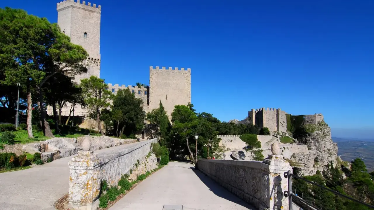 Erice: cosa vedere? Un antico castello domina il paesaggio, con torri imponenti e mura merlate che si stagliano contro il cielo azzurro.