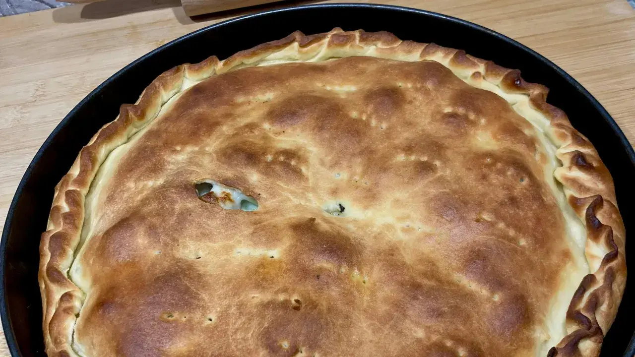 Schiacciatella pane dorata e fragrante, appena sfornata in teglia, con un ripieno invitante che fa capolino da una fessura.