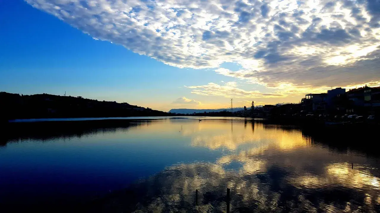 Tramonto sui Ganzirri, con cielo nuvoloso e riflessi dorati sull'acqua. Un luogo incantevole da esplorare.