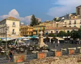 Piazza animata nel pizzo calabro centro storico, con tavoli all'aperto di ristoranti e palazzi storici sullo sfondo.