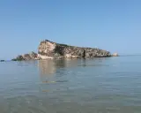 La Rocca San Nicola a Licata, imponente roccia calcarea che emerge dal mare cristallino, sotto un cielo azzurro.