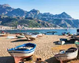 Barche da pesca sulla spiaggia di Giardini Naxos, con Taormina sullo sfondo montuoso.