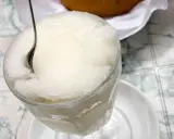 Un bicchiere colmo di granita al gelsomino, con un cucchiaino che affonda nella sua consistenza ghiacciata. Perfetta per una pausa rinfrescante.