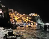 Scilla illuminata di notte, un incanto da visitare a piedi. Case colorate e il castello arroccato sul promontorio si specchiano nel mare.