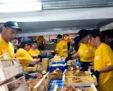 Persone in maglietta gialla servono fritto misto in un evento serale. Un'ottima idea per cosa fare a Salerno la sera, gustando specialità locali.