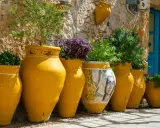 Vasi gialli decorati con un volto femminile e piante rigogliose, un angolo pittoresco da scoprire tra le cose da vedere a Bagheria.