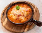 Piatto fumante di gnocchi al forno, uno dei piatti tipici della Campania, con pomodoro e mozzarella filante, guarnito con basilico.