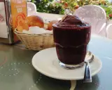 Un bicchiere di granita messinese, scura e invitante, accanto a soffici brioche in un cestino. Un'immagine che sa di sole e colazioni siciliane.
