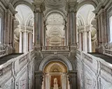 Magnifici interni della Reggia di Caserta: scalinate imponenti, marmi pregiati e volte maestose creano un'atmosfera regale.