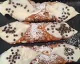 Cannoli siciliani, un classico di cosa si mangia in Sicilia: croccanti cialde ripiene di crema e gocce di cioccolato.