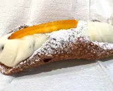 Cannolo ripieno di ricotta, uno dei dolci tipici di Palermo, cosparso di zucchero a velo e decorato con scorza d'arancia candita.