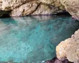Acque cristalline nella baia di San Cataldo, con rocce calcaree che creano un'atmosfera suggestiva.
