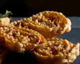 Cartellate, dolci tipici della Puglia, ricoperte di miele e confettini colorati, con un rametto di agrifoglio sullo sfondo.
