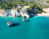 Scogliere bianche a picco sul mare turchese, con rocce isolate e vegetazione lussureggiante. Un vero angolo di paradiso tra le spiagge più belle della Puglia.