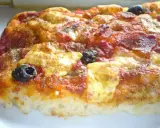 Una fetta di pizza muddiata, con pomodoro, formaggio filante, salame e olive nere, condita con erbe aromatiche.