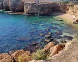 Acque cristalline e scogliere dorate incorniciano la spiaggia di Massolivieri, un angolo di paradiso con rocce affioranti.