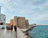 Passeggiata serale a Monopoli: il castello, il mare azzurro e una nave da crociera.