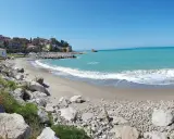 Spiaggia di Lampare a Tusa, con mare turchese, case colorate sul promontorio e rocce sulla riva.
