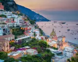Vista mozzafiato dal **punto panoramico Positano**, con case colorate aggrappate alla scogliera e barche nel mare al tramonto.