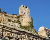 La torre dell'orologio di Modica, con il suo quadrante romano, domina il paesaggio sotto un cielo azzurro.