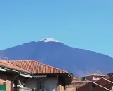 Vista dell'Etna fumante, un'imponente montagna che domina il paesaggio. Un'ottima meta per scoprire cosa vedere a Bronte, con i suoi tetti rossi in primo piano.
