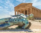 Statua di Icaro caduto nella Valle dei Templi, Agrigento. Il tempio dorico sullo sfondo è il Tempio della Concordia.