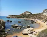 Splendida spiaggia la rocca licata con acque cristalline e scogliere rocciose. Turisti si godono il sole e il mare.