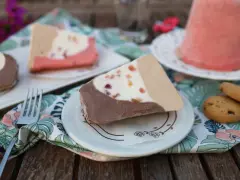 Fette di gelato a pezzo siciliano, con cioccolato, crema e frutta candita, servite su piattini con tovaglioli floreali.
