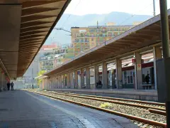 Binario di una delle fermate treno Palermo, con un treno fermo e persone in attesa sotto la pensilina.