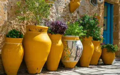 Vasi gialli decorati con un volto femminile e piante rigogliose, un angolo pittoresco da scoprire tra le cose da vedere a Bagheria.