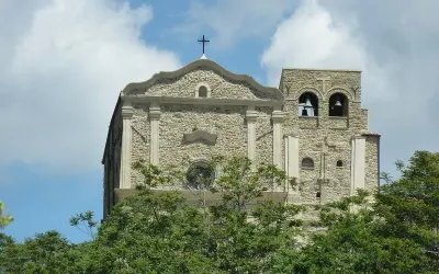 Chiesa Madre di Corleone, un gioiello di pietra con campanile e campane, tra il verde degli alberi. Un luogo da scoprire tra le cose da vedere a Corleone.